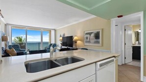 Een keuken met een groot raam, een spoelbak en een deur naar een balkon.