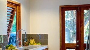Cocina con isla integrada, lavaplatos y ventana con vista a follaje.