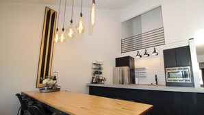 Une cuisine moderne avec une table à manger en bois, des chaises noires et des luminaires suspendus.