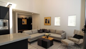 Un salon moderne avec un canapé d’angle, une table basse et un fauteuil à motifs.