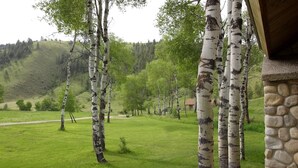 A stone building with birch trees in the foreground. - Aspen Cabin at Rye Creek Lodge (Darby)