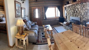 A rustic cabin interior with a stone wall, wooden furniture, and a stone fireplace. - Aspen Cabin at Rye Creek Lodge (Darby)