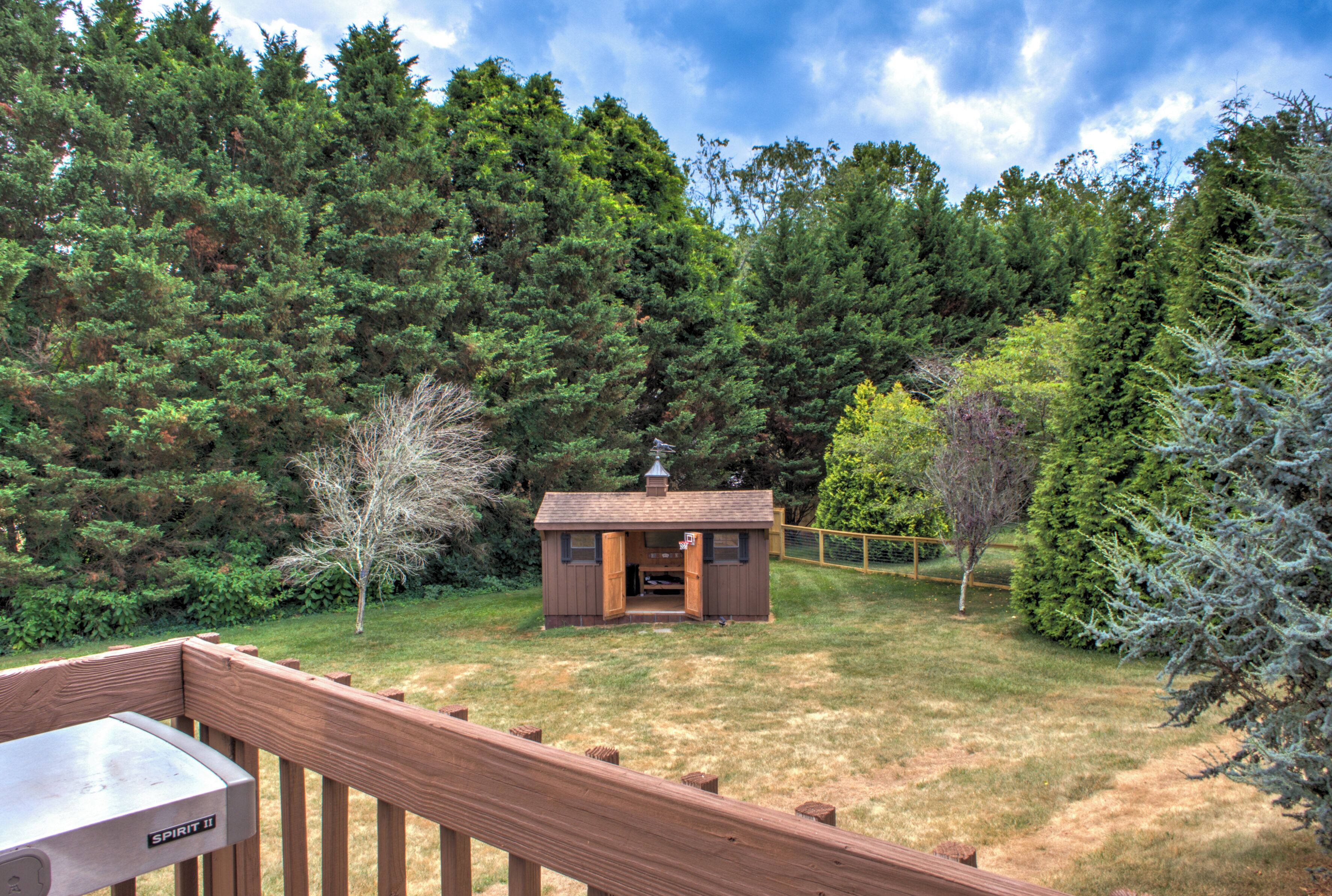 A cabin with a wooden deck, surrounded by dense forest.