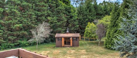 A cabin with a wooden deck, surrounded by dense forest.