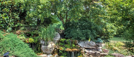 A garden with a small waterfall, surrounded by rocks and various plants.
