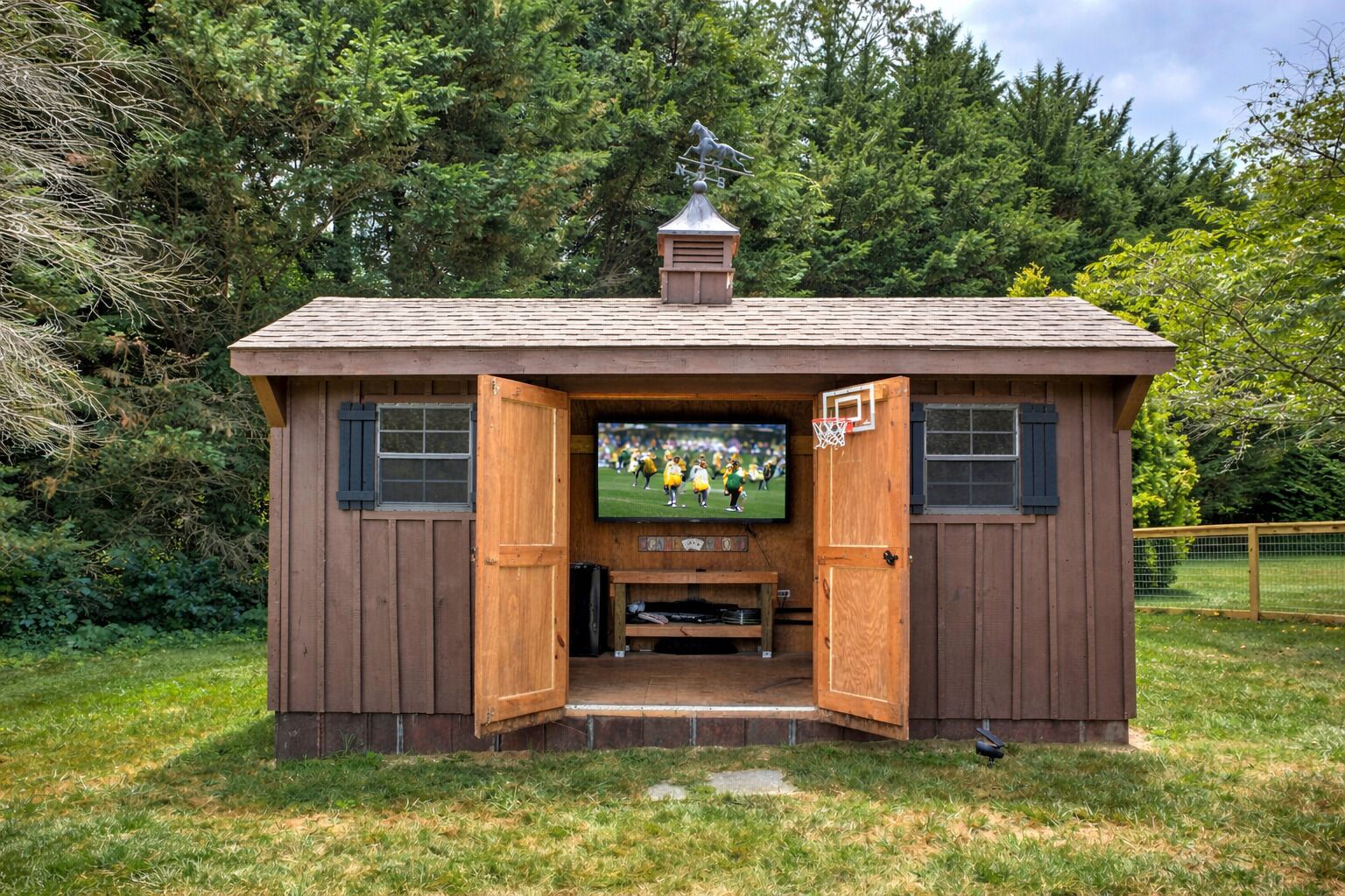 A wooden structure with a television screen, open doors, and a small basketball hoop.