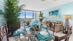 A dining area with a glass table, chairs, and a large potted plant.