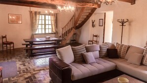 Ein gemütliches Wohnzimmer mit einer Couch, einem Esstisch und einer Treppe.
