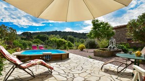 Eine Steinterrasse mit Pool, Liegestühlen und einem Tisch mit gelber Teekanne.