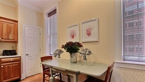 A dining area with a table, chairs, a vase with flowers, and framed artwork on the wall. - 1bd, 1.5ba Historic District and River Front-Walk to Everything! (Savannah)