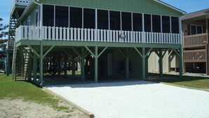 A green building with a covered patio and a white fence. - Shell House  - Less than a block to beach access and recently updated! (Sunset Beach)