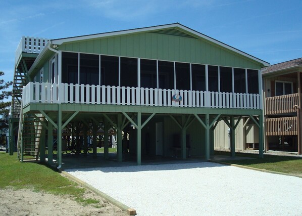 A green building with a covered patio and a white fence.