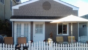 Une maison d’habitation avec une clôture en bois peinte en blanc, une véranda et une boîte aux lettres.