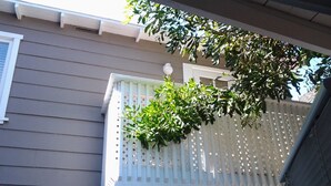 Un immeuble résidentiel doté d’un balcon blanc, d’une clôture blanche et d’un arbre aux feuilles vertes.