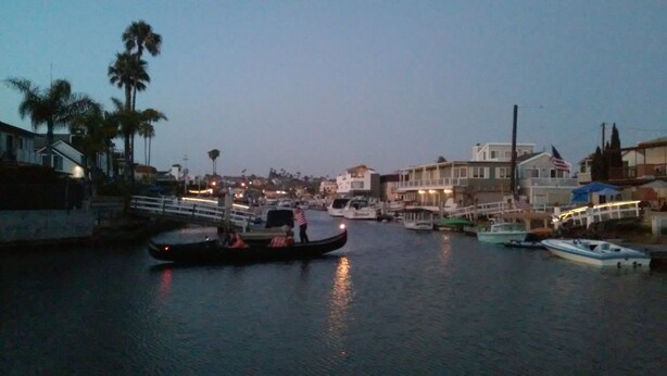 Un port de plaisance avec des bateaux amarrés, un pont et des bâtiments le long de la rive.