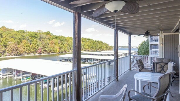 A covered outdoor area with a view of a lake, chairs, and a table. - Lazy Days V-01 - Five Bedroom Apartment, Sleeps 12 (Osage Beach)