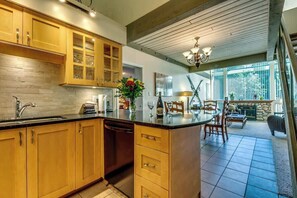 A kitchen with wooden cabinets, a dishwasher, and a dining area with chairs and a table.