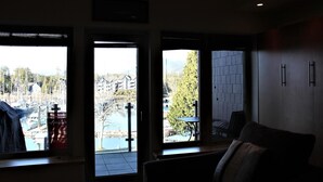 A room with three large windows, a sofa, and a table.