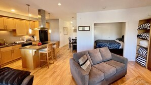 A compact living space with a kitchenette, a sofa, and a bed in the background.