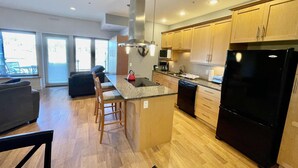 A modern kitchen with wooden cabinets, a black refrigerator, and a central island with bar stools.