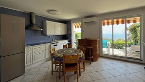 Una cocina con armarios blancos, un refrigerador de acero inoxidable y una zona de comedor con una mesa redonda y sillas.