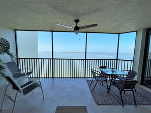 Ein Balkon mit Tisch und Stühlen, einem Deckenventilator und Blick auf das Meer.