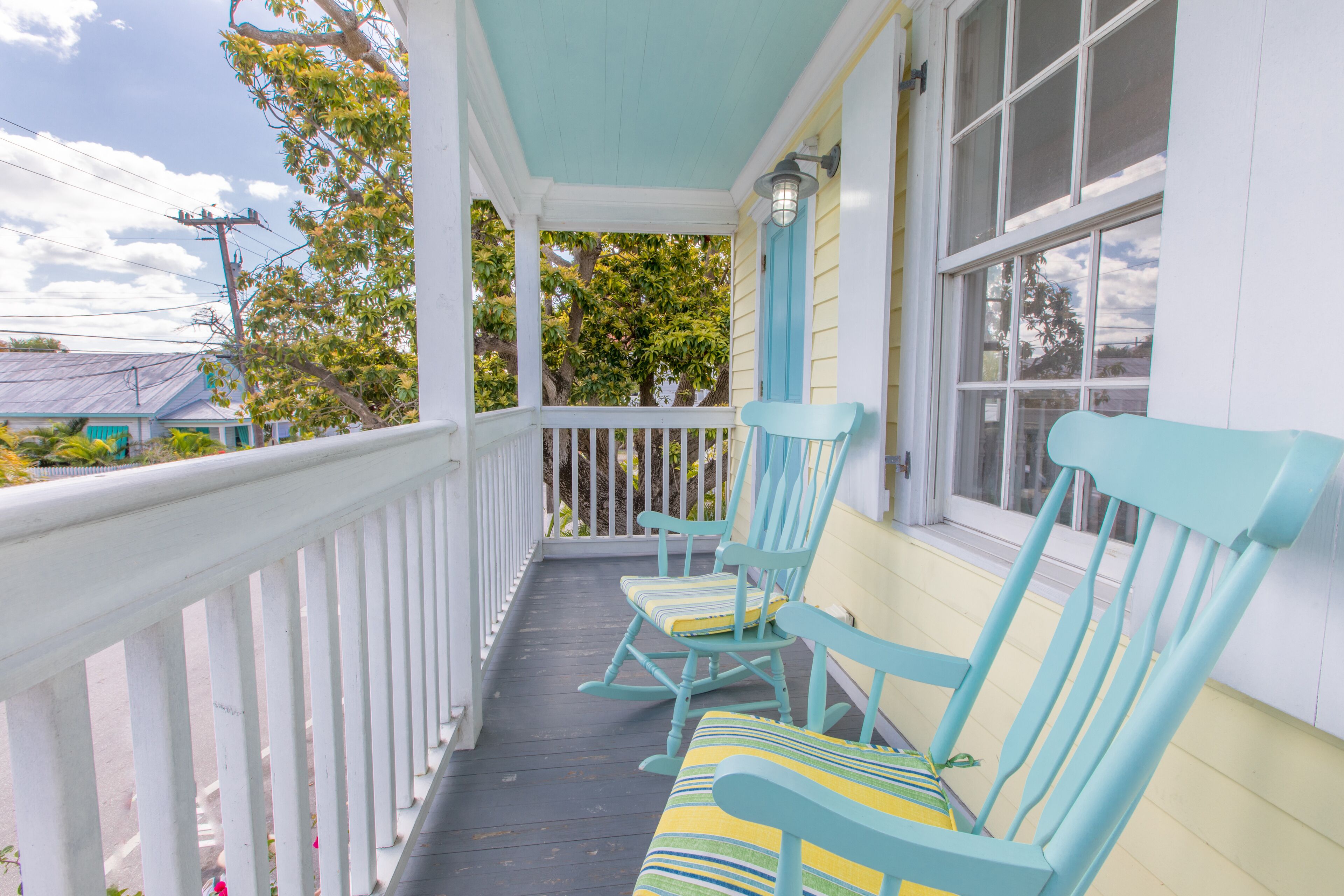 A porch with two rocking chairs and a white railing.