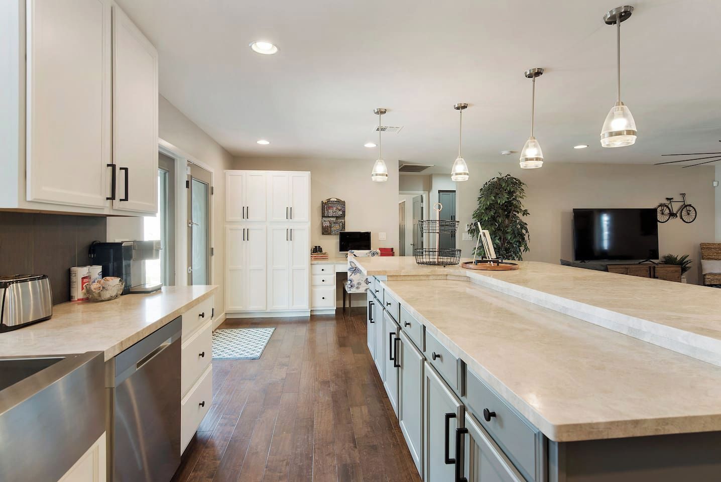 A modern kitchen with a large island, stainless steel appliances, and pendant lighting.