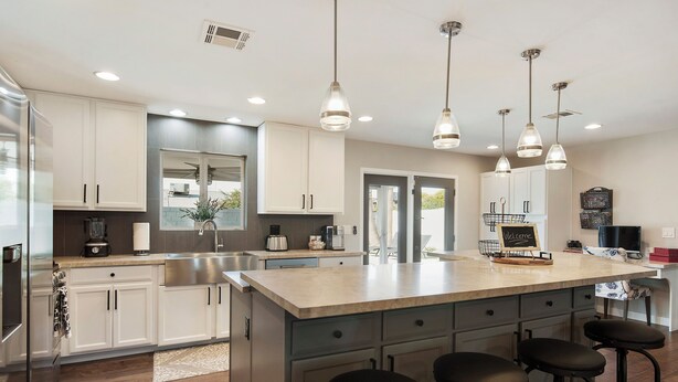 A modern kitchen with white cabinets, a large island with bar stools, stainless steel appliances, and pendant lighting. - Old Town Scottsdale All around VACATION experience! Heated Pool & Media Room (Scottsdale)