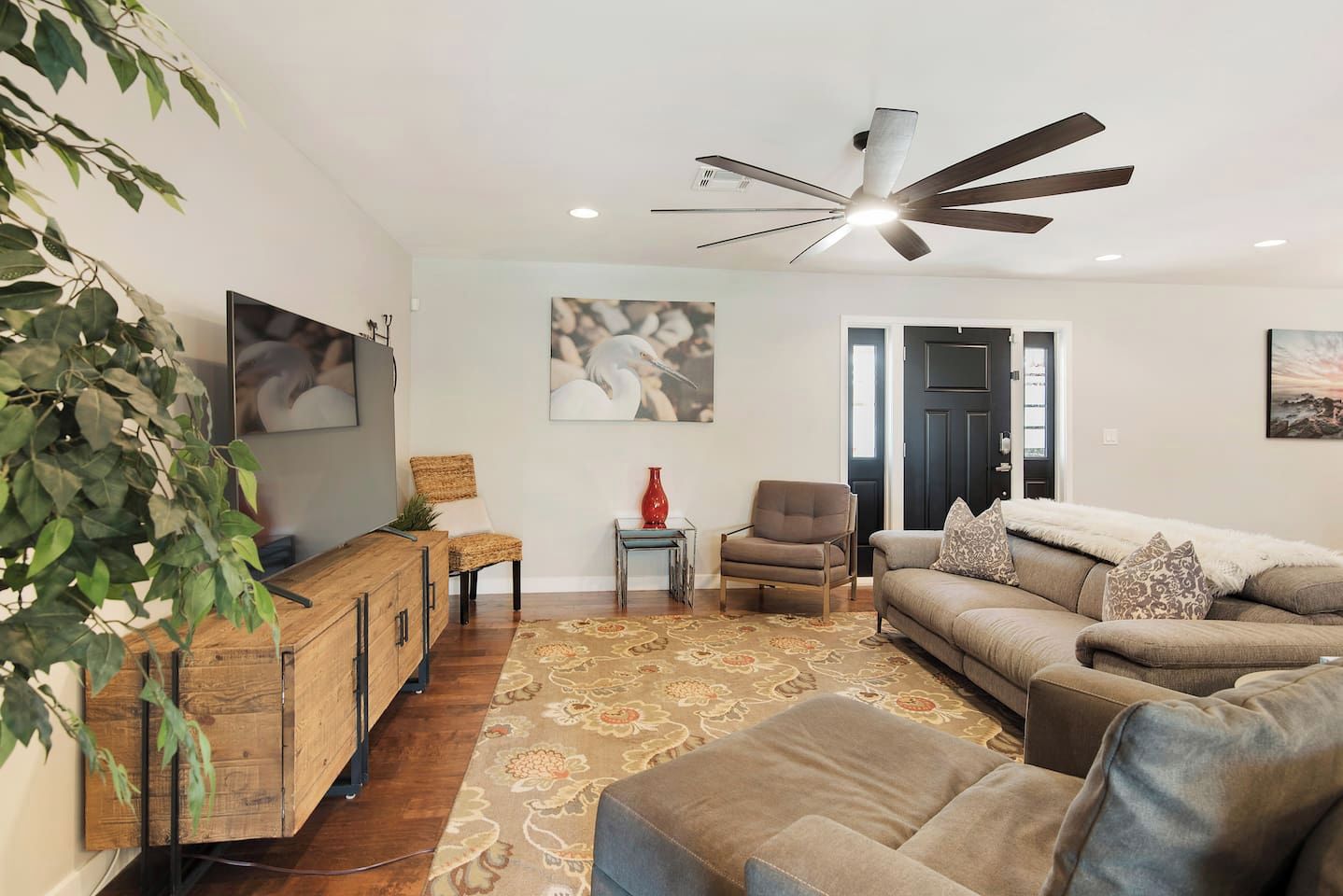A living room with a television, a ceiling fan, a sofa, a coffee table, and a decorative rug.