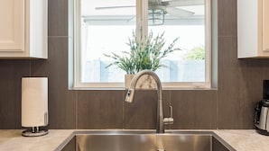 A modern kitchen with a stainless steel sink, a window with a view of the outside, and a potted plant on the windowsill. - Old Town Scottsdale All around VACATION experience! Heated Pool & Media Room (Scottsdale)