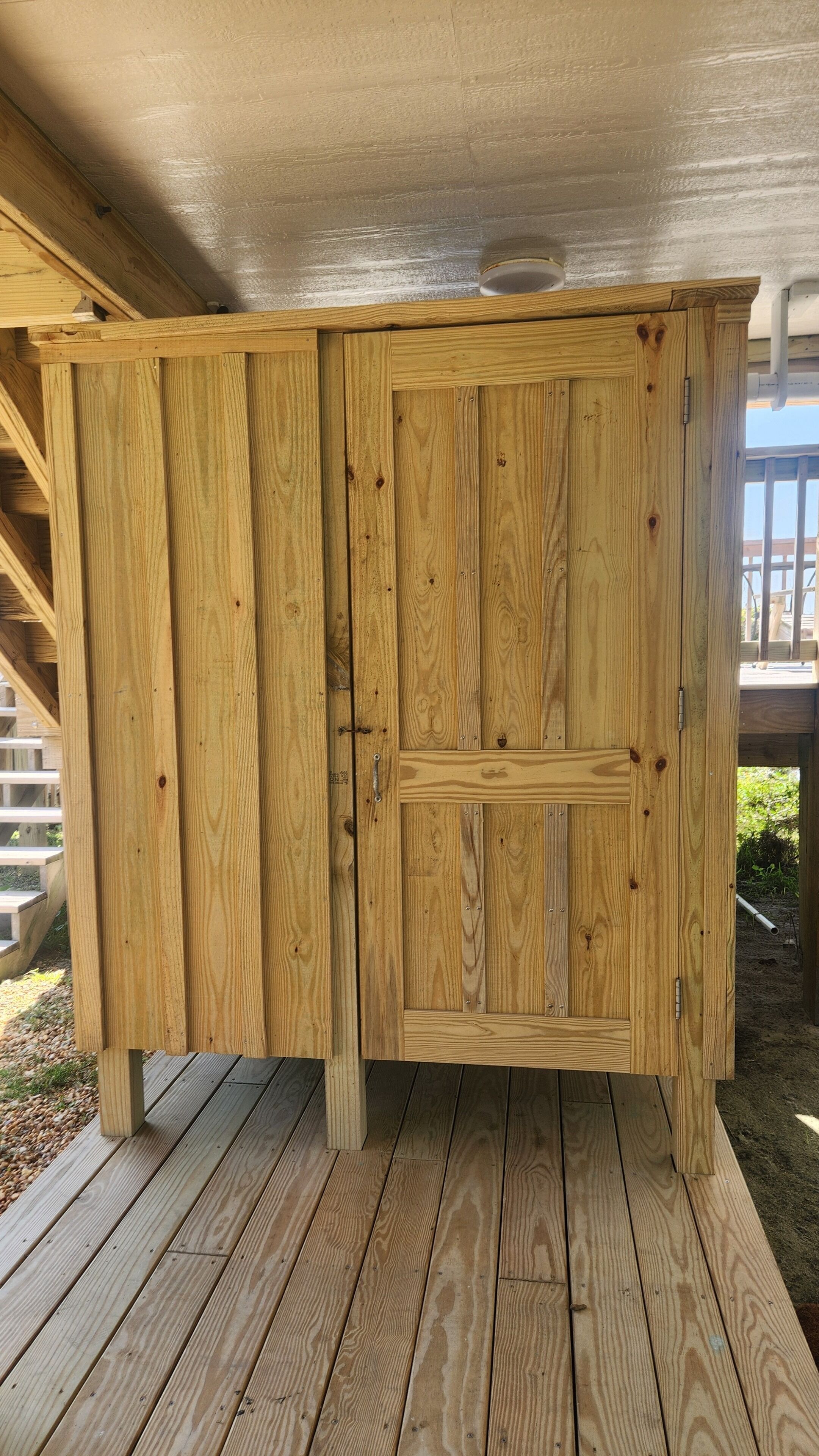A wooden structure with a door, possibly a shed or storage unit, on a wooden deck.