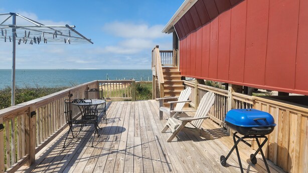 Eine Holzterrasse mit Meerblick, einem Grill und Sitzgelegenheiten im Freien.