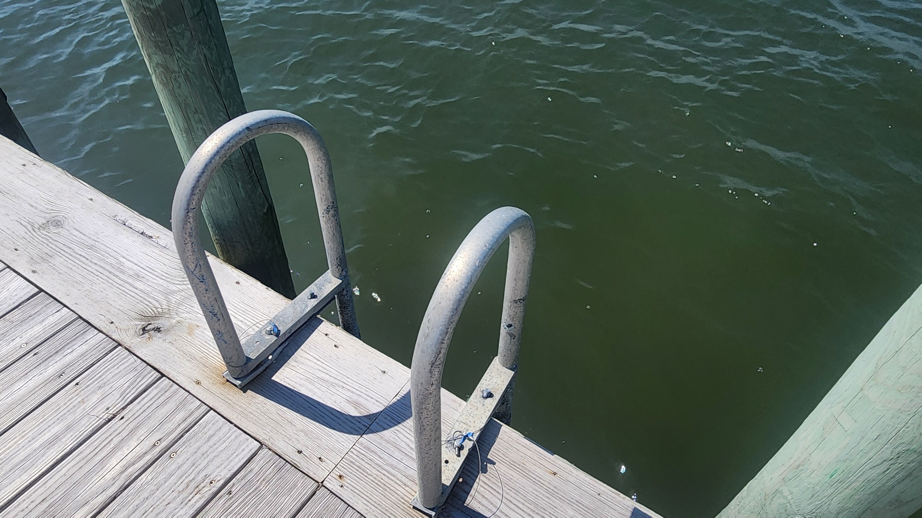 Une jetée en bois avec des garde-corps métalliques qui s’étendent au-dessus de l’eau.