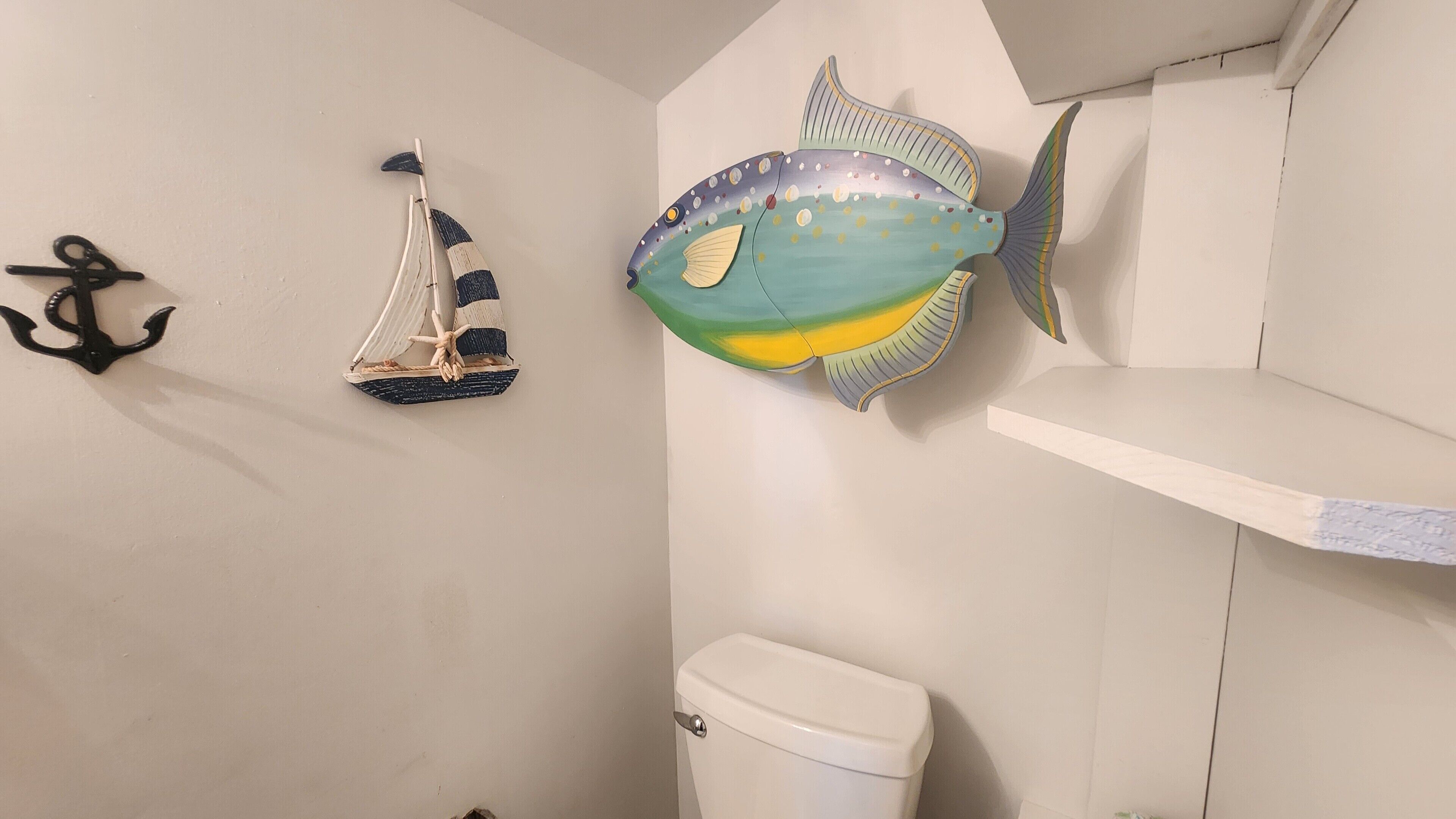 Een badkamer met een toilet, een wastafel en een wandplank.