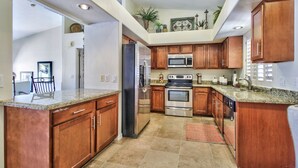 A spacious kitchen with granite countertops, wooden cabinets, stainless steel appliances, and a built-in oven.
