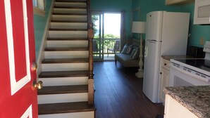Una cocina con escalera de madera, un refrigerador y vistas al exterior.