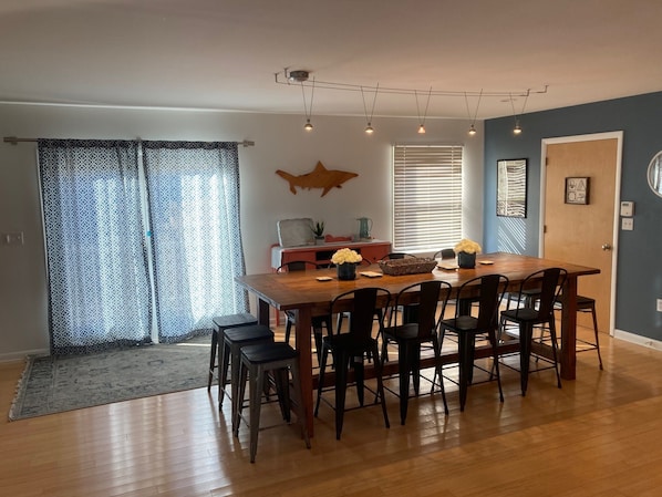 A dining area with a wooden table and chairs, a patterned curtain, and a decorative wall piece.