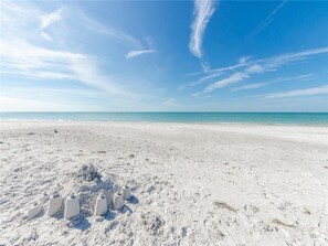 Een strand met een heldere lucht en een rustige zee.
