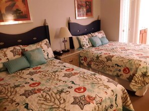 Dos camas con estampados florales y de estrellas a juego, una lámpara de noche y una mesita de noche.