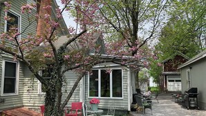 A house with a covered porch, a patio with outdoor furniture, and a garage. - Stay-cation In Charmified Village Guest House! (Aurora)