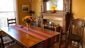 A dining room with a wooden table, chairs, a vase of flowers, and a fireplace. - Stay-cation In Charmified Village Guest House! (Aurora)