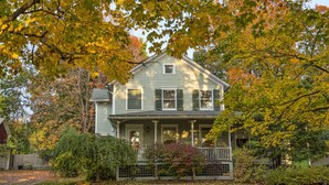 A two-story house with a porch, surrounded by trees with autumn foliage. - Stay-cation In Charmified Village Guest House! (Aurora)