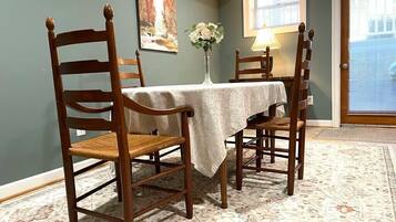 Un comedor con una mesa preparada para cuatro personas, rodeada de sillas de madera con asientos de mimbre.