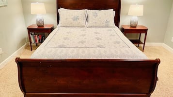 A large, dark wood-framed bed with two matching pillows and two bedside tables with lamps.