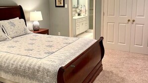 A bedroom with a large bed, a nightstand with a lamp, a dresser, and a door leading to another room. - MOUNT VERNON RETREAT 🌸 (Alexandria)