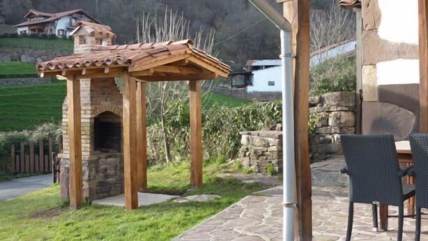 A stone-built outdoor kitchen with a chimney, a wooden pergola, and a stone patio. - Labakizarra House for 8 people (Baztan)