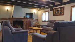 A living room with a fireplace, a television, and a painting on the wall. - Labakizarra House for 8 people (Baztan)