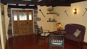 A cozy room with a wooden door, a checkered sofa, a small table with a vase, and a chair. - Labakizarra House for 8 people (Baztan)