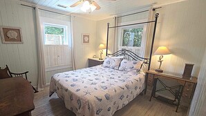 Une chambre à coucher avec un lit à baldaquin, deux tables de chevet avec des lampes, un bureau en bois et une chaise.
